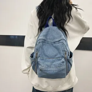 Sac à dos en jean bleu clair pour femmes avec plusieurs poches, porté par un modèle