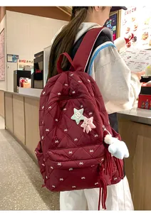 Close-up of wine red quilted backpack with bow embroidery and plush star charm