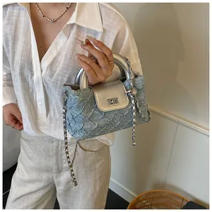 Detail der hellblauen Denim-Handtasche mit silberner Metallkette und strukturierter Falte