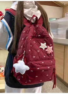 Detail of quilted burgundy backpack with bow embroidery and star plush pendant