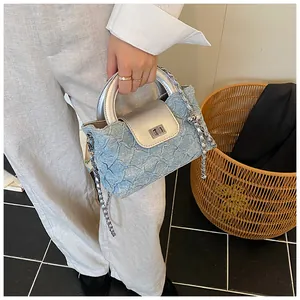Detail der hellblauen Denim-Umhängetasche mit silbernem Metallgriff und Kettenriemen
