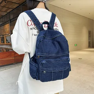 Vista trasera detallada de una mochila de mezclilla azul oscuro usada por una modelo