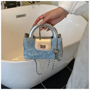 Detail der hellblauen Handtasche mit Faltenstruktur, Silbergriff und Kettengurt