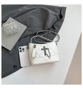Close-up of quilted white leather bag with gothic metal cross and skull zipper detail