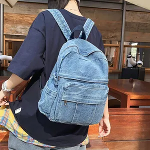 Detalle de mochila de tela vaquera lavada con múltiples bolsillos con cremallera y correas