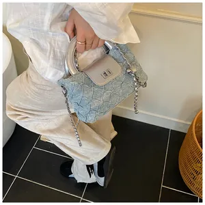 Detail der hellblauen strukturierten Handtasche mit silbernem Ringgriff und Kettenriemen