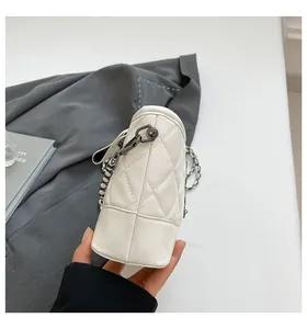 Detail shot of white quilted leather texture and dark grey metal chain strap on bucket bag