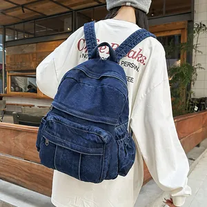 Detalle de la mochila de mezclilla azul oscuro con bolsillos laterales y pespuntes