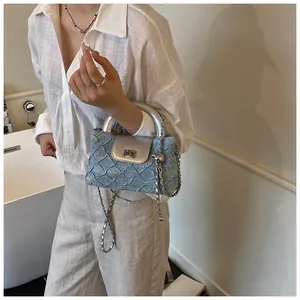 Detail der blauen Denim-Beuteltasche mit silbernem Lederbesatz und Kettenriemen