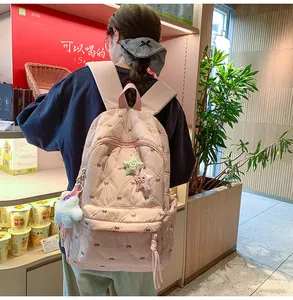 Detailed view of pink quilted backpack with bow embroidery and star-shaped pendant charm