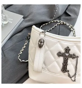 Detail of white quilted bag with skull charm, gothic cross, and leather chain strap