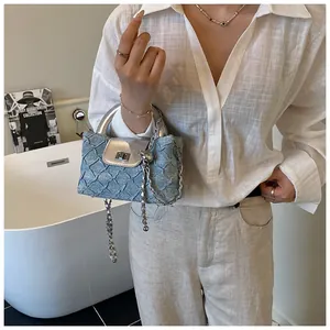 Detail der hellblauen Tasche mit Denim-Textur, silberner Klappe und Metallkettenriemen