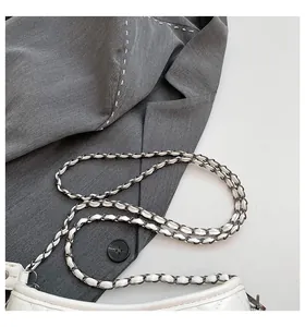 Close-up of quilted pattern and silver chain strap on white faux leather shoulder bag