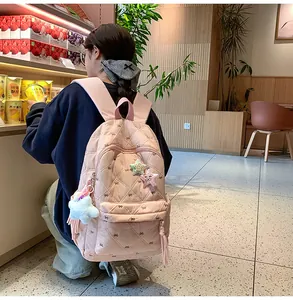 Detailed view of pink quilted backpack with bow embroidery and star-shaped plush charm