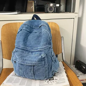 Primer plano de una mochila de mezclilla lavada azul con bolsillo frontal en silla de madera