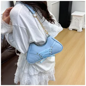 Detail of light blue sneaker-style shoulder bag with criss-cross ribbon and chain strap