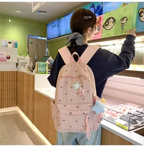 Detail of pink quilted backpack with bow embroidery and star pendant in a cafe setting