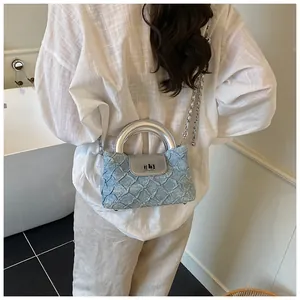 Detail der hellblauen Denim-Beuteltasche mit Rautensteppung und silberner Kette