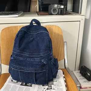 Detalle de una mochila vaquera azul retro con costuras blancas sobre una silla de madera