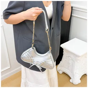 Silver metallic crescent bag with white lace-up ribbons and gold chain strap detail