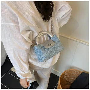 Detail der hellblauen Jeans-Stofftasche mit Silbergriff und quadratischem Schloss