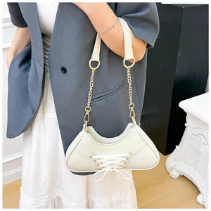 Detail of cream balletcore shoulder bag with lace-up sneaker design and chain strap