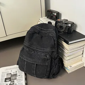 Detalle de la mochila de mezclilla lavada con costuras blancas en contraste y bolsillos
