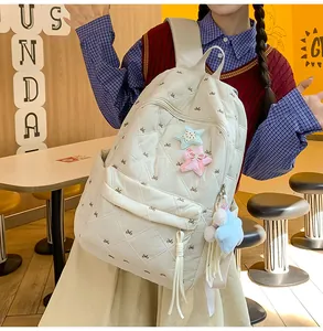 Detail of beige quilted backpack with bow embroidery and colorful star charms