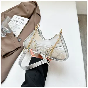 Detail shot of silver ballet-style handbag featuring cross-lace straps and golden chain