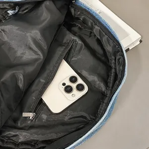 Detalle del interior de la mochila de mezclilla con forro negro y bolsillo con cremallera