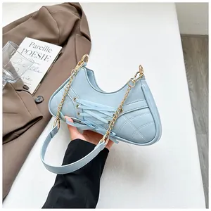 Detail of light blue quilted underarm bag with decorative lace-up design and gold chain