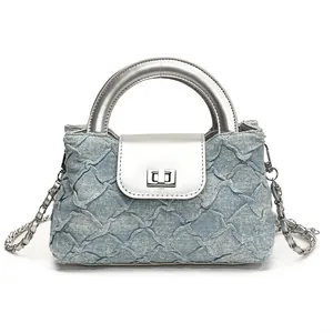 Blaue Denim Beuteltasche mit Steppmuster und silbernem Metallgriff sowie Kettenriemen