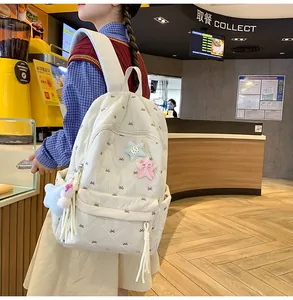 Detail of cream quilted backpack with bow embroidery and colorful plush star patches