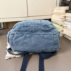 Detalle de mochila de tela vaquera lavada con correas azul marino reforzadas