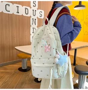 Detail of cream quilted backpack with colorful star patches and soft blue plush charm