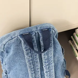 Detalle de la textura vaquera duradera y costuras reforzadas en la mochila azul