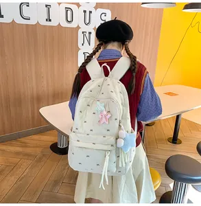 Close-up of cream quilted backpack with bow embroidery and cute star charms