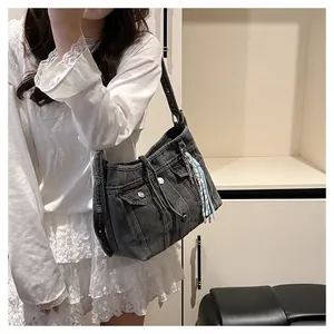 Vue détaillée du sac à bandoulière en denim noir avec franges bleues et détails métalliques