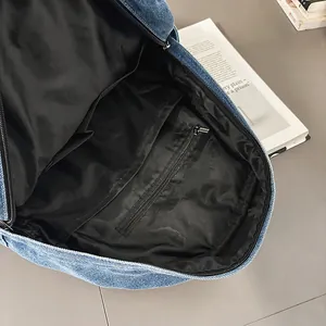 Vista detallada del interior de la mochila de mezclilla con forro negro y compartimentos