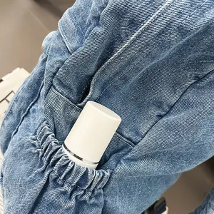 Detalle de mochila vaquera azul claro con bolsillo lateral elástico y botella blanca