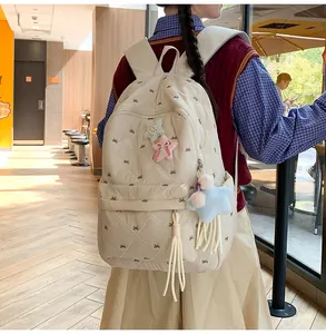 Detail of cream quilted backpack featuring bow embroidery and soft plush star pendants