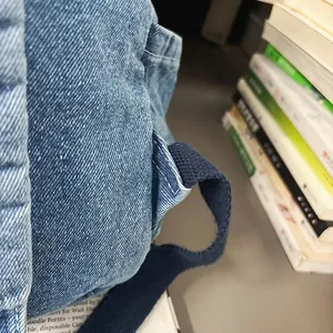 Detalle de cerca de los tirantes de la mochila de mezclilla lavada y costuras finas