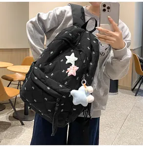 Detail of quilted black puffer backpack with white bows and star plush charms