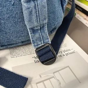 Detalle de la correa de mochila vaquera y hebilla de metal negro sobre tela azul