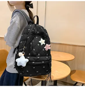 Side view of black quilted backpack with bow embroidery and star plush pendant