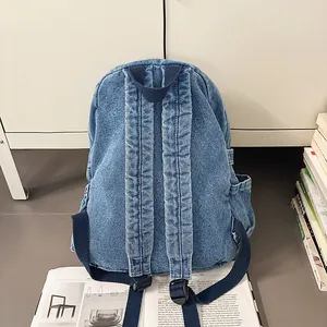 Vista posterior detallada de una mochila de mezclilla azul lavado con correas anchas y bolsos