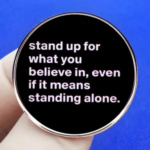 Pin's rond en émail avec citation inspirante sur fond noir et bordure dorée