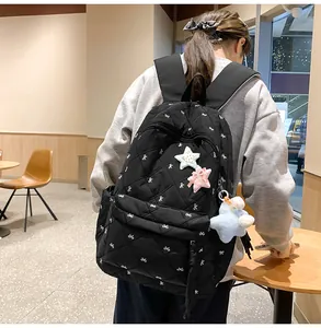 Close-up of black quilted backpack with white bow embroidery and star-shaped charms