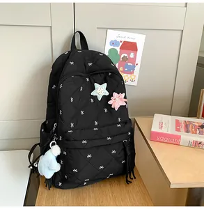 Close-up of black quilted nylon backpack featuring white bow prints and star patches