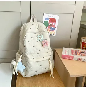 Close-up of cream quilted backpack featuring delicate bow embroidery and star charms